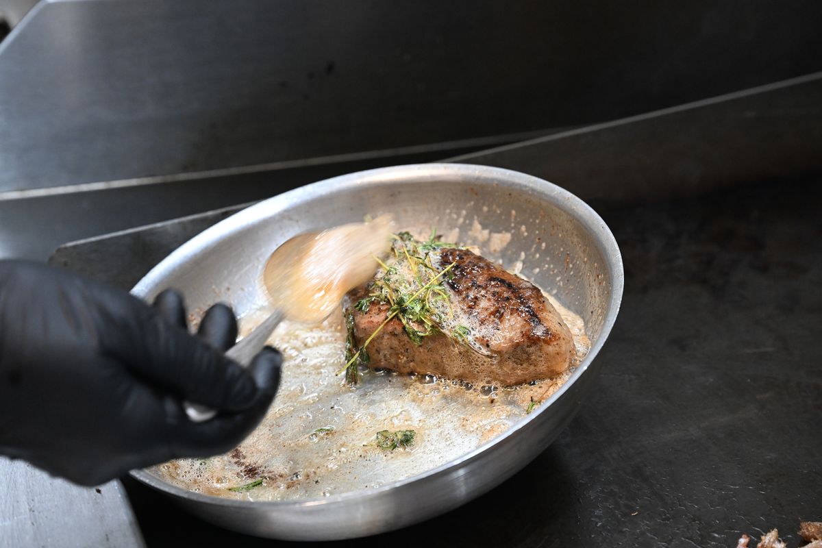 Chef de cuisine Shaun Ratty prepares a steak on the grill, then places it in a butter bath in a pan at a new French restaurant, simply named Bowery, at 230 W. Riverside, Avenue, which some may remember as the dive bar and record store called Garageland. It's a now an open, well-lit space with a French cuisine menu.  (Jesse Tinsley/The Spokesman-Review)