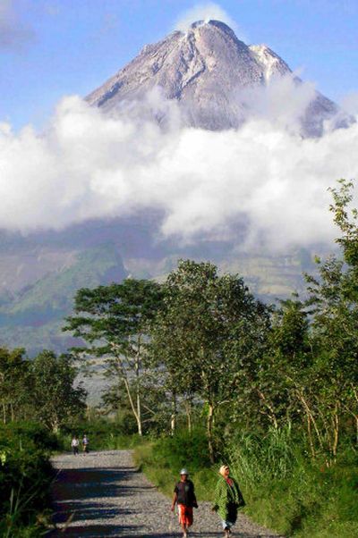 
Villagers in Kemiren walk Saturday with Mount Merapi as a backdrop in central Java, Indonesia. 
 (Associated Press / The Spokesman-Review)