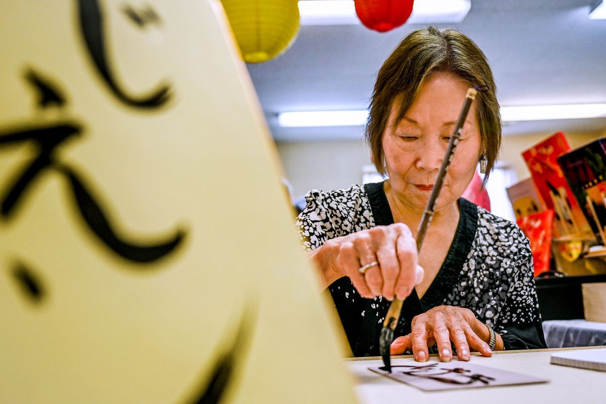 Local artist Keiko Van Holt uses the hiragana method of Japanese writing during the Spokane Buddhist Temple’s 10th annual Obon Festival on Sunday.  (Kathy Plonka/The Spokesman-Review)