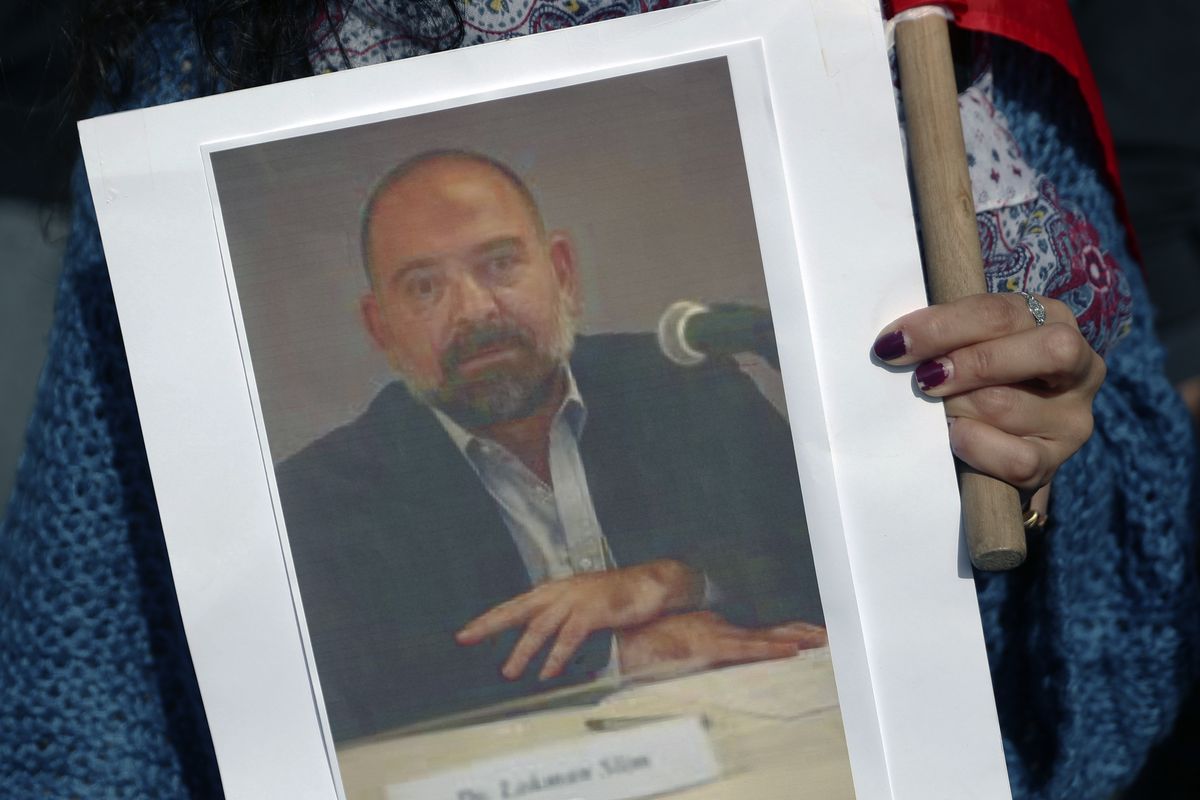 An anti-Hezbollah protester holds a picture of Lokman Slim, a longtime Shiite political activist and researcher, who has been found dead in his car, during a protest in front of the Justice Palace in BeirutBeirut, Lebanon, Thursday, Feb. 4, 2021.  (Bilal Hussein)