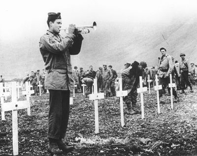 In this Aug. 1943 file photo, a bugler sounds taps during a memorial service while a group of G.I.s visit the graves of comrades who fell in the reconquest of Attu Island, part of the Aleutian Islands of Alaska. (Associated Press)