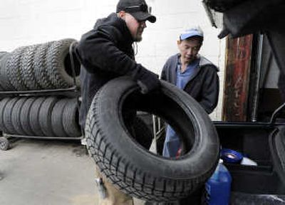 
Aaron Junes, owner of Big Bubba's Wheels and Tires near the corner of Market and Garland in Spokane,  loads a pair of studded snow tires into Tam Pham's trunk last week.  Junes had just removed the winter tires and replaced them on the wheels with Pham's summer tires. 
 (Dan Pelle / The Spokesman-Review)