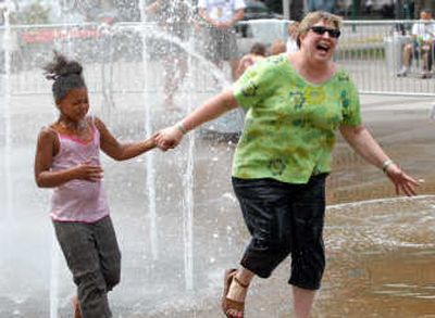 Nine-year-old Faith Cook and her mentor, Kristy Stender-Bratcher, run through the Riverfront Park fountain Tuesday. Stender-Bratcher helps manage a program that matches mentors with children of incarcerated parents.
(Jesse Tinsley / The Spokesman-Review)