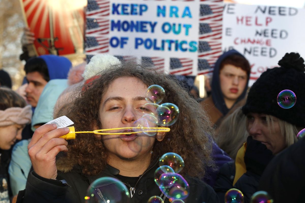 J.J. Miller, 17, of Baltimore, Md., blows bubbles as crowds arrive for the March for Our Lives rally in support of gun control, Saturday, March 24, 2018, in Washington. (Alex Brandon / Associated Press)