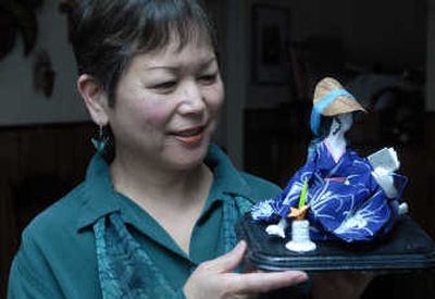 
Patti Reiko Osebold of North Spokane holds one of her dolls, made of clay and dressed in textured paper garments. At left, two figures engaged in the martial art of kenjitsu.
 (Photos by JESSE TINSLEY / The Spokesman-Review)