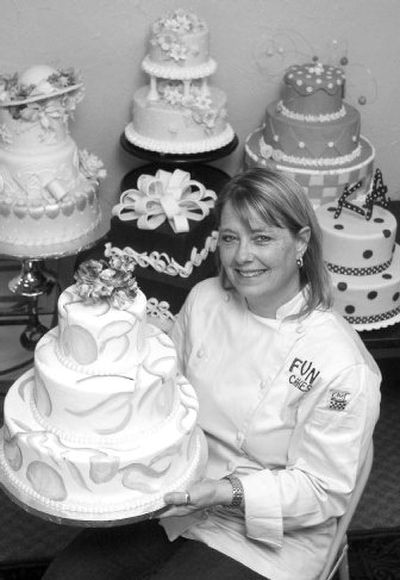 
Kimberly Aya sits with samples of rental cakes, which are made of plastic foam except for a small insert of real cake. 
 (BPN / The Spokesman-Review)