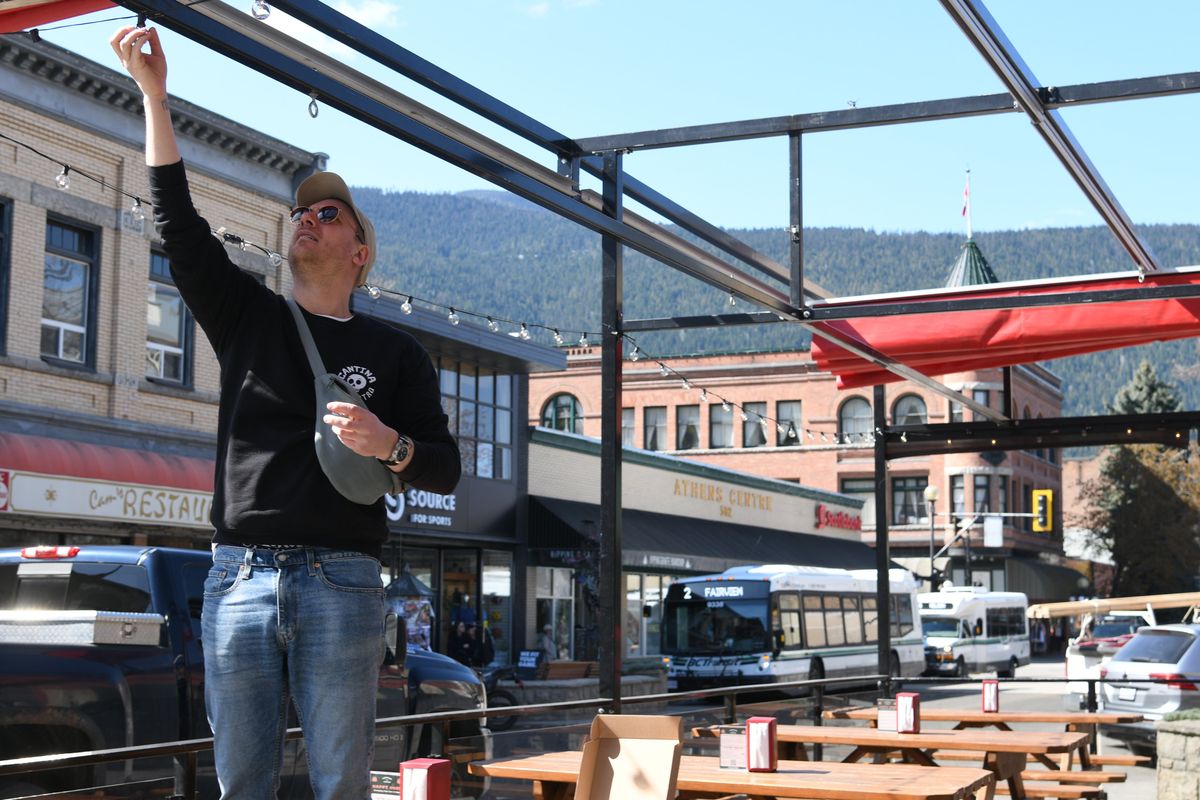 Alex Beaudoin, operations manager of Cantina del Centro, replaces lightbulbs for the restaurant’s street patio Thursday morning in Nelson, British Columbia. Beaudoin said he expects to see more business from domestic tourism this year as many Canadians choose not to visit the U.S. (James Hanlon/The Spokesman-Review)