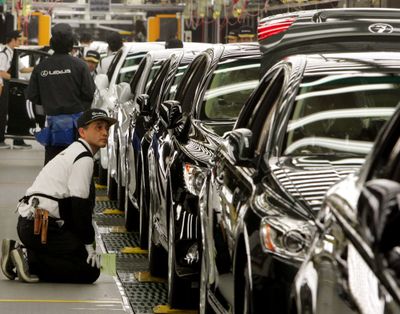 In this June 28 file photo, a Toyota Motor Corp. worker kneels to check a Lexus at the Japanese automaker’s flagship production line for luxury Lexus models in Tahara, central Japan. The Japanese auto giant has lowered its global vehicle sales forecast for the second time this year. (File Associated Press / The Spokesman-Review)