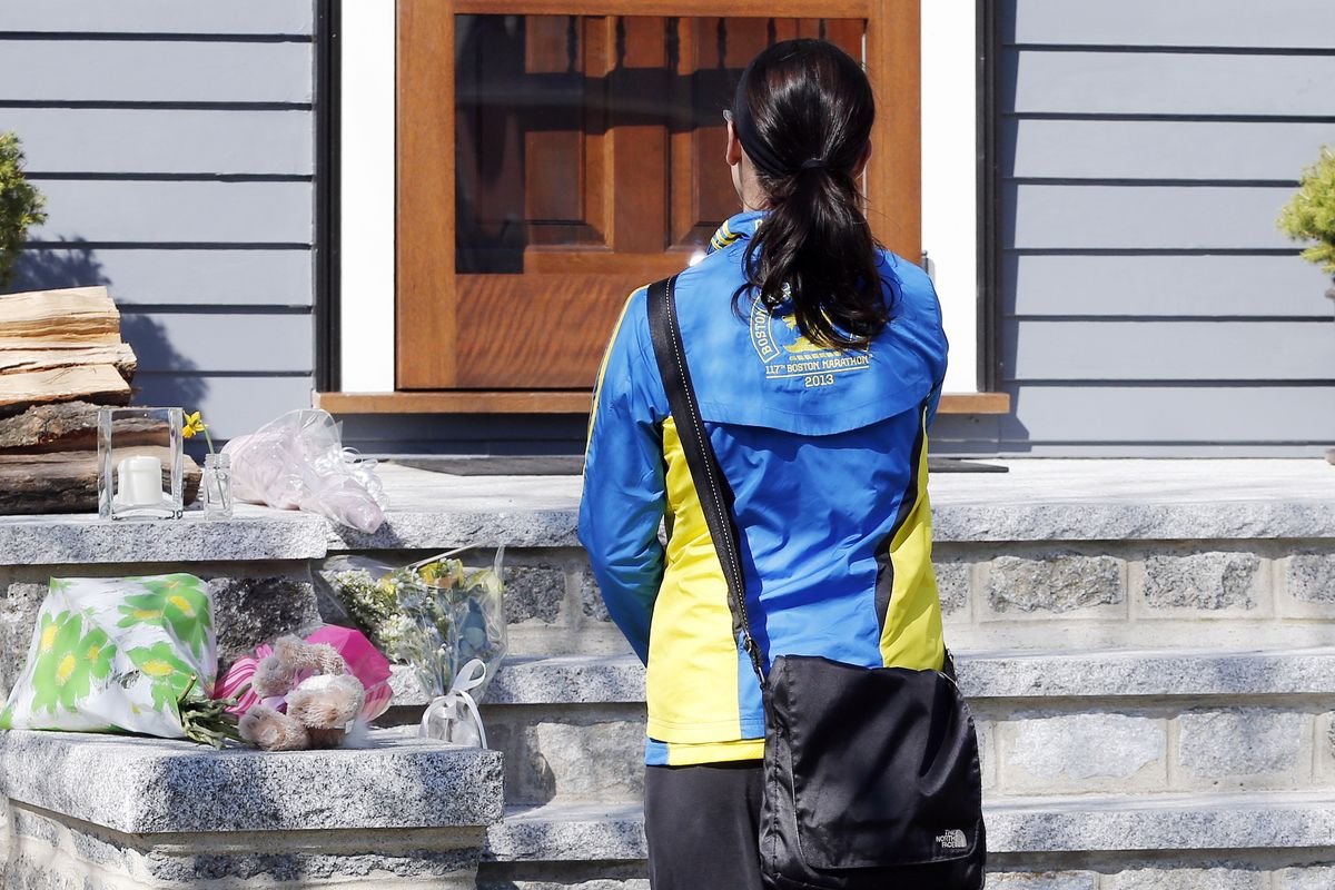 Runner Megan Cloke pauses after placing flowers on the doorstep of the Richard house in the Dorchester neighborhood of Boston,Tuesday, April 16, 2013. Martin Richard,8, was killed in Mondays