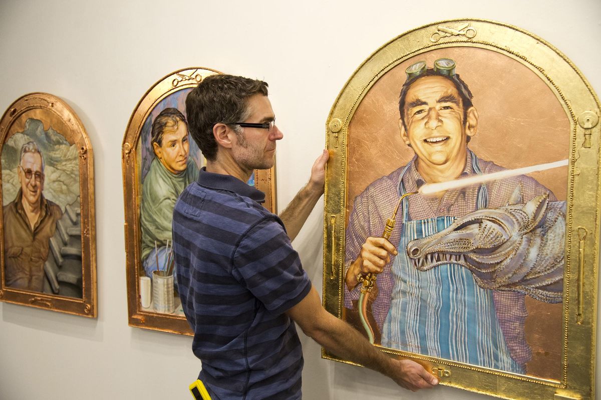 Volunteer and ceramic artist Chris Kelsey hangs a portrait series by artist Ken Spiering in the Chase Gallery at Spokane City Hall Tuesday. The show being hung is a tribute to Bob Gilmour, a longtime art instructor. (JESSE TINSLEY jesset@spokesman.com)