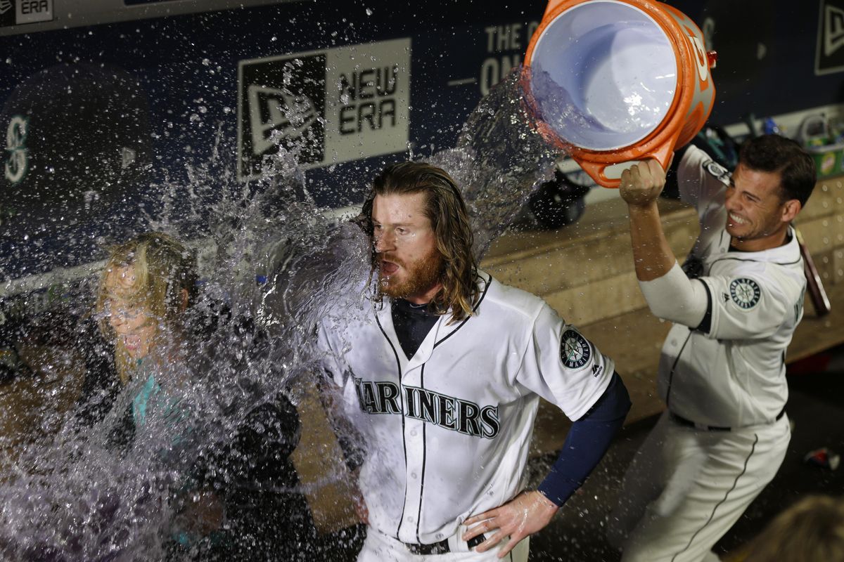 Seattle’s Ben Gamel, center, and Root Sports reporter Angie Mentink are doused by Mariners’ Danny Valencia during an interview after Gamel scored the winning run on a walk-off single hit by Nelson Cruz during the 10th inning against the New York Yankees on July 22, 2017, in Seattle. The Mariners won 6-5. (Ted S. Warren / AP)