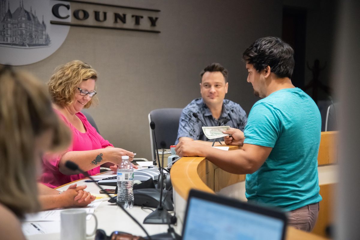 Phil Johnson, on right, has his winning bids processed after buying two properties, one for $514 and $614, on Friday, Aug. 16, 2019, at the Spokane County Public Works Building. Spokane County auctioned off 18 small properties Friday morning, with starting bids ranging from $50 to $34,000. (Colin Mulvany / The Spokesman-Review)