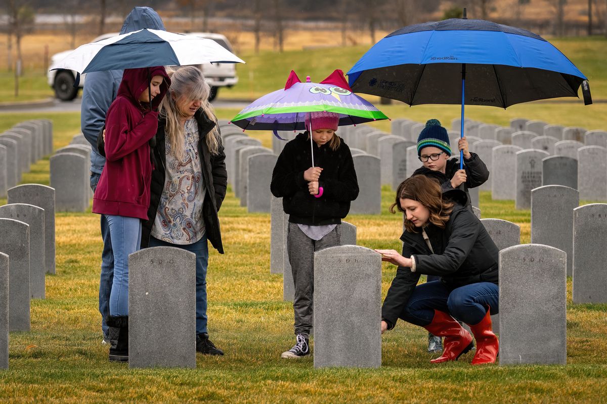 On Veterans Day, the Alent family – Josh, left, who stands behind 12-year-old Ellie and Brenda, 9-year-old Macie, Cari and 5-year-old James – tend the gravestone of veteran John Gerald Alent, who served in the U.S. Air Force during the Vietnam War and died in January at 74.  (COLIN MULVANY/THE SPOKESMAN-REVIEW)