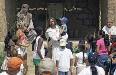 
Les Cheveldayoff, center, portraying Jesus, interacts with visitors while holding Jared Bell, 2 of Ripley, Tenn., after a performance called 