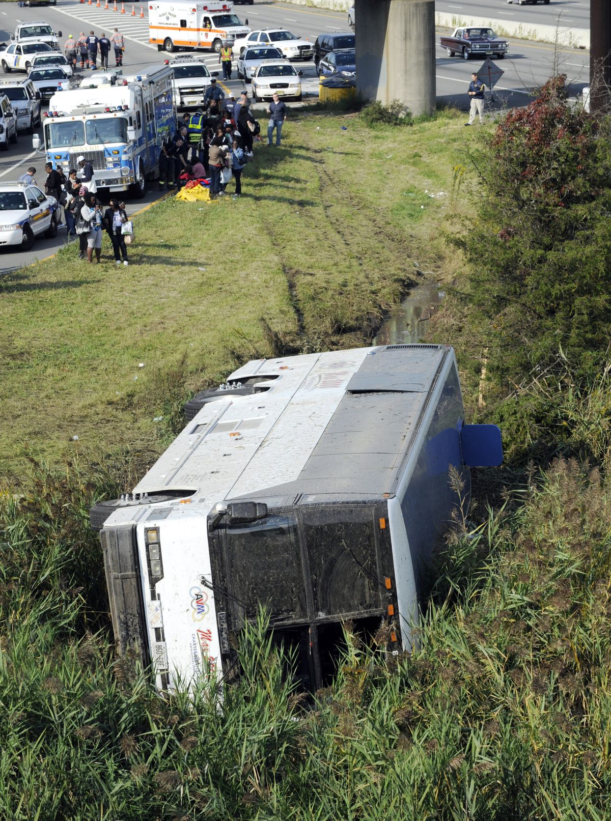 Rescue workers and passengers stand by after a bus overturned in a ditch at an exit ramp off Route 80 in Wayne, N.J. Saturday, Oct. 6, 2012. The chartered tour bus from Toronto carrying about 60 people overturned on an interstate exit ramp. Three people have been taken to hospital with non-life-threatening injuries. (Bill Kostroun / Fr51951 Ap)