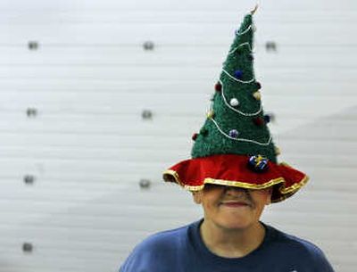 
Fern Swecker, a 12-year volunteer at the Christmas Bureau, wears a holiday hat as she greets visitors to the singles recipient gift table at the Spokane County Fair and Expo Center on Thursday. 
 (Dan Pelle / The Spokesman-Review)