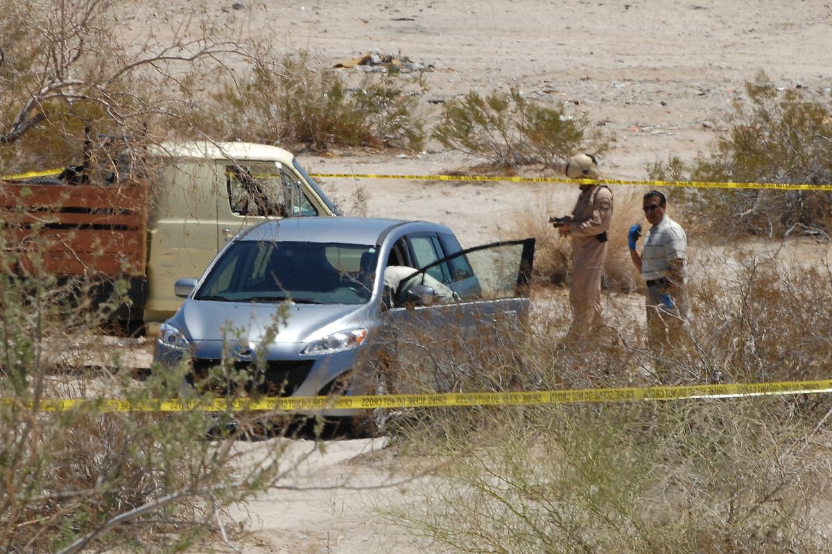 Investigators check a vehicle thought to be that of a man suspected of shooting five people Thursday, June 2, 2011 in Yuma, Ariz.  and the Wellton-Mohawk Valley. The man allegedly took his own life in the vehicle found in the desert approximately 13 miles northeast of Yuma. (Randy Hoeft / The Yuma Daily Sun)