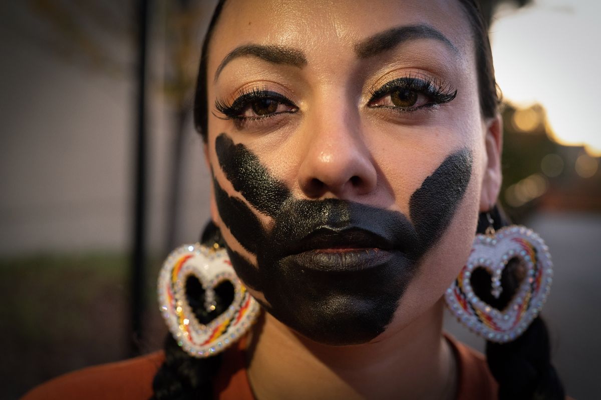 Kailee Koller, a member of the Spokane Tribe, wears the symbol of missing and murdered indigenous woman and children on her face as she and her family attend the Indigenous Peoples Day event Monday night in the plaza next to Spokane City Hall.  (Colin Mulvany/The Spokesman-Review)