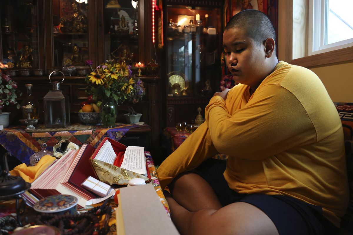 Jalue Dorje, 14, says his morning prayers, Tuesday, July 20, 2021, in Columbia Heights, Minn. When he was an infant, Jalue, now 14, was identified as the eighth reincarnation of the lama Terchen Taksham Rinpoche. After finishing high school in 2025, Jalue will head to northern India and join the Mindrolling Monastery, more than 7,200 miles (11,500 kilometers) from his home. (Jessie Wardarski)