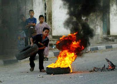 
A Palestinian boy puts another tire on the fire during a demonstration in Jebaliya refugee camp, northern Gaza Strip, on Thursday. Palestinian leader Yasser Arafat, who led the Palestinian people over four decades, died at a Paris hospital early Thursday. 
 (Associated Press / The Spokesman-Review)