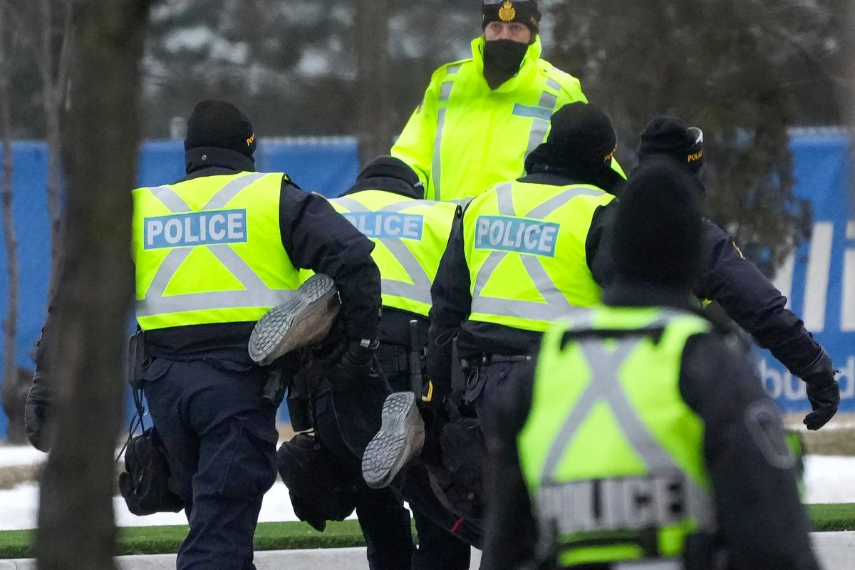 Police arrest a person Sunday as they removed all truckers and supporters blocking access to the Ambassador Bridge, linking Detroit and Windsor, Ontario. (Nathan Denette)