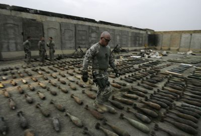 A U.S. soldier  walks through munitions at a joint U.S.-Iraqi army base in Sadr City on Tuesday. The munitions were seized  during recent operations in the Shiite enclave.  (Associated Press / The Spokesman-Review)