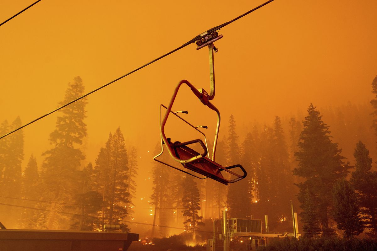 Seen in a long camera exposure, the Caldor Fire burns as a chairlift sits motionless at the Sierra-at-Tahoe ski resort on Sunday in Eldorado National Forest, Calif. The main buildings at the ski slope’s base survived as the main fire front passed.  (Noah Berger)