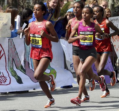 FILE - In this Monday, April 21, 2014, file photo Buzunesh Deba, left, of Ethiopia, runs in a group of elite female participants past Wellesley College during the 118th Boston Marathon in Wellesley, Mass. Deba was named the 2014 Boston Marathon winner Monday with a time of 2:19:59 following the disqualification of Rita Jeptoo for doping. (Mary Schwalm / Associated Press)
