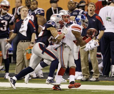 Giants’ Mario Manningham made the play of the game when he hauled in a pass over Patriots’ Sterling Moore and Patrick Chung, center. (Associated Press)