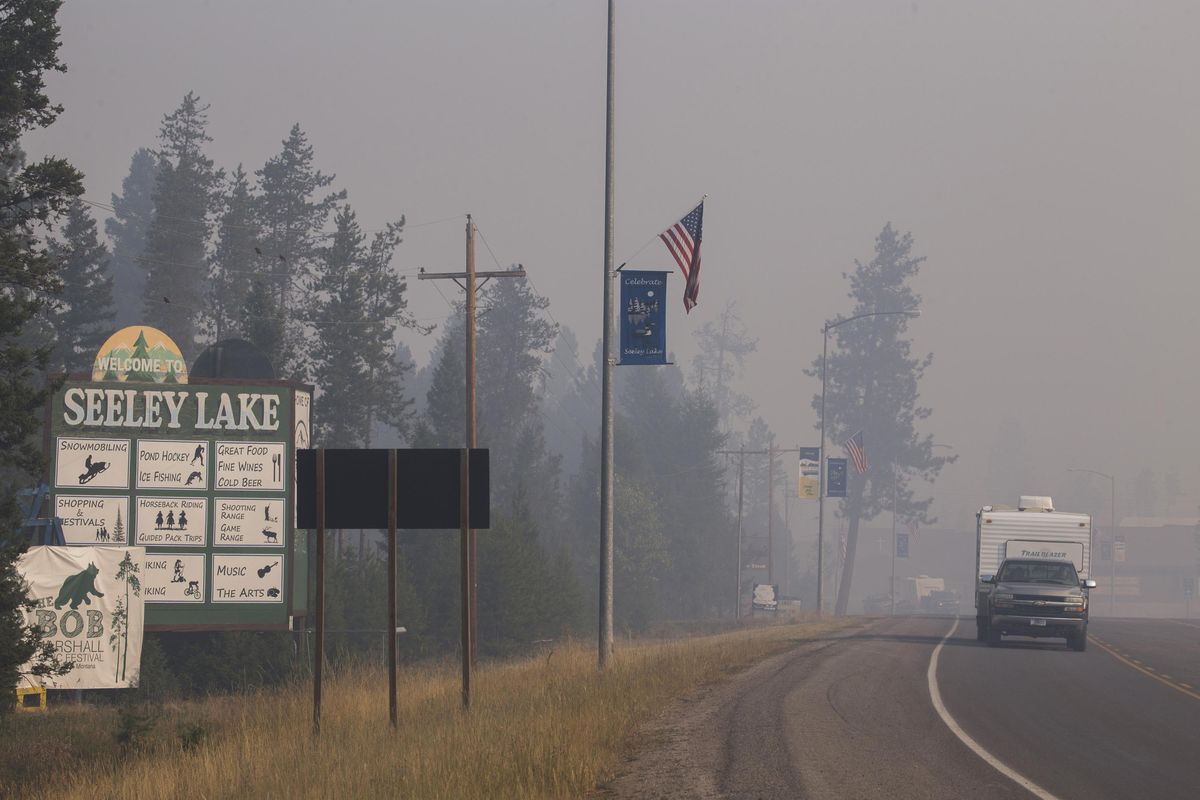 In this photo provided by the U.S. Forest Service, a pickup truck pulls a camper through the wildfire smoke in Seeley Lake in Missoula County, Mont., on Thursday, Aug. 10, 2017. (U.S. Forest Service)