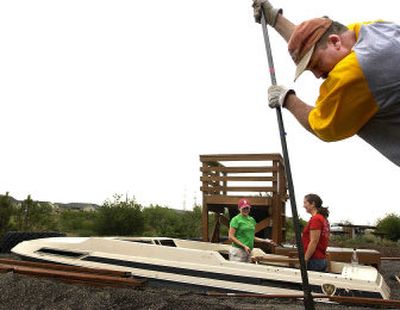 
John Garcia digs a posthole while Cathy Grenier, left, and Lisa Oakes, all from the Naval and Marine Corps Reserve Center of Spokane, paint a buried boat at a playground in northeast Spokane on Friday during Days of Caring. Days of Caring was started in 1994 to connect local businesses and nonprofits. 
 (Jed Conklin / The Spokesman-Review)