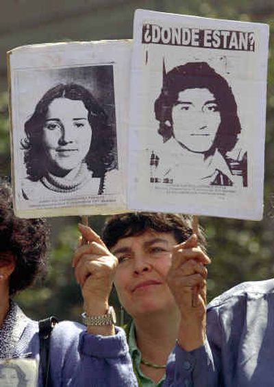 
Relatives of dissidents who disappeared during the dictatorship of  Gen. Augusto Pinochet hold posters of them reading 