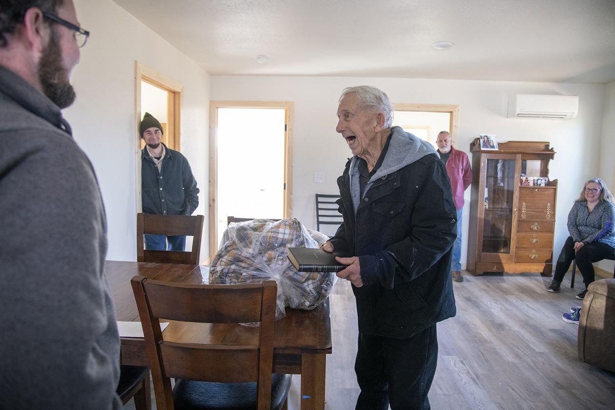 Jim Jacobs, right, an elderly resident of Malden, Washington, expresses his gratitude after he receives a bed comforter and a new Bible from Toby Yoder, left, inside Jacobs