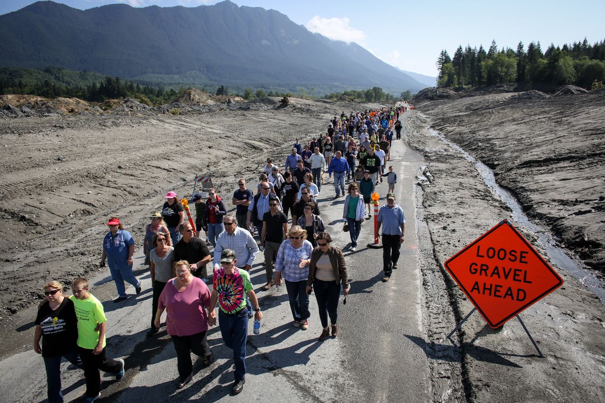 Before the highway is reopened to vehicles, hundreds, including residents of Oso, Darrington and Arlington, Wash., walk on state Route 530 near Oso on Saturday to pay tribute to those killed in a mudslide March 22. (Associated Press)