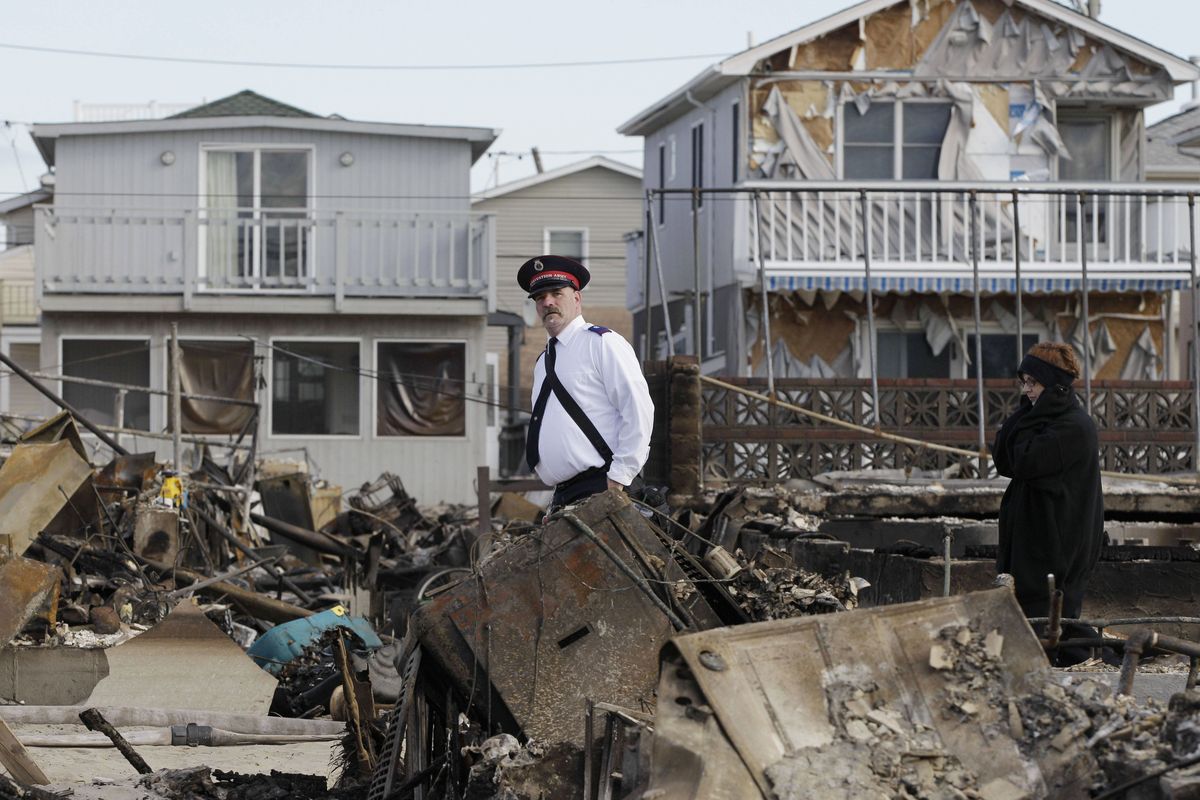 A representative of the Salvation Army walks past homes destroyed by Superstorm Sandy in Breezy Point, Sunday, Nov. 4, 2012, in New York. The beachfront neighborhood heavy populated by firefighters and police officers was devastated during the storm when a fire pushed by Sandy