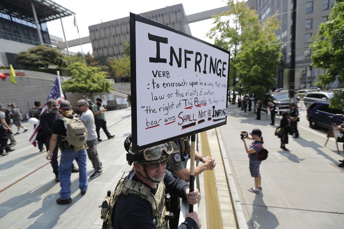 A protester stands on the side of the street with members of Patriot Prayer and other groups advocating for gun rights at a rally, Saturday, Aug. 18, 2018, at City Hall in Seattle. (Ted S. Warren / Associated Press)