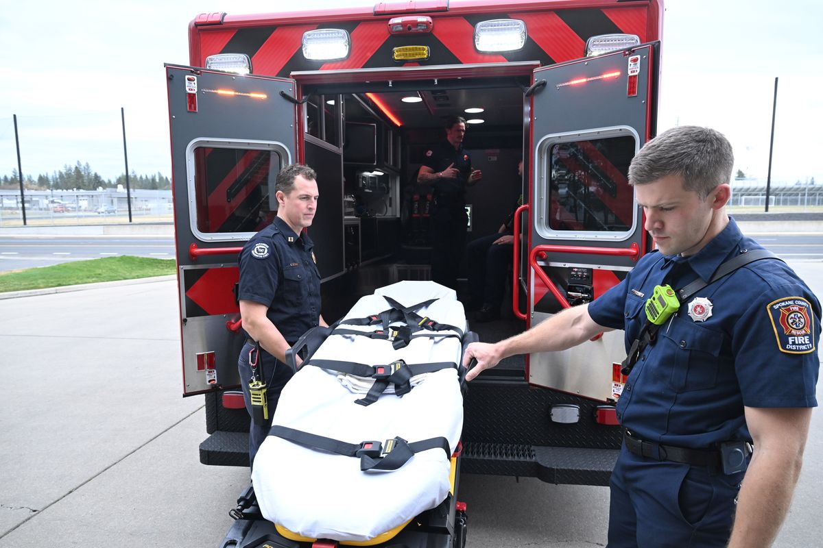 Firefighters Matthew Von Steuben, left, and Erik Holm, right, demonstrate the removal of the gurney from one of the new ambulances purchased by Spokane County Fire District 9 to begin providing ambulance service to the Mead area starting July 1.  (Jesse Tinsley/THE SPOKESMAN-REVIEW)