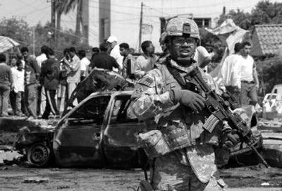 
A U.S. soldier secures the scene after   a car bombing killed at least 12 people Thursday. 
 (Associated Press / The Spokesman-Review)