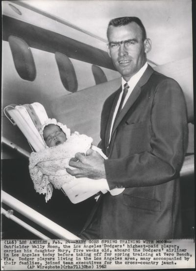 FILE - Wally Moon, former players for the Los Angeles Dodgers, carries his daughter aboard the Dodgers' airliner in Los Angeles today before taking off for spring training at Vero Beach, Florida, on Feb. 24, 1962. (Associated Press)