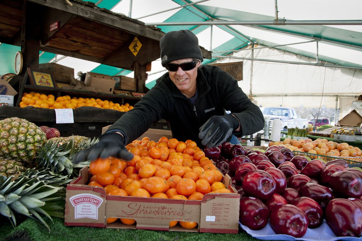 Rusty Keele sorts through produce Tuesday at the corner of Sprague Avenue and Blake in Spokane Valley. (Dan Pelle)