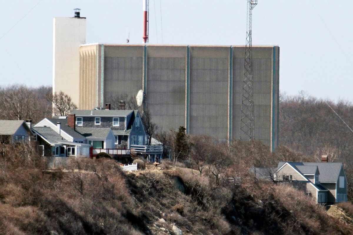 FILE - A portion of the Pilgrim Nuclear Power Station is visible beyond houses along the coast of Cape Cod Bay, in Plymouth, Mass., March 30, 2011. Pilgrim, which closed in 2019, was a boiling water reactor. Water constantly circulated through the reactor vessel and nuclear fuel, converting it to steam to spin the turbine. The water was cooled and recirculated, picking up radioactive contamination.  (Steven Senne)