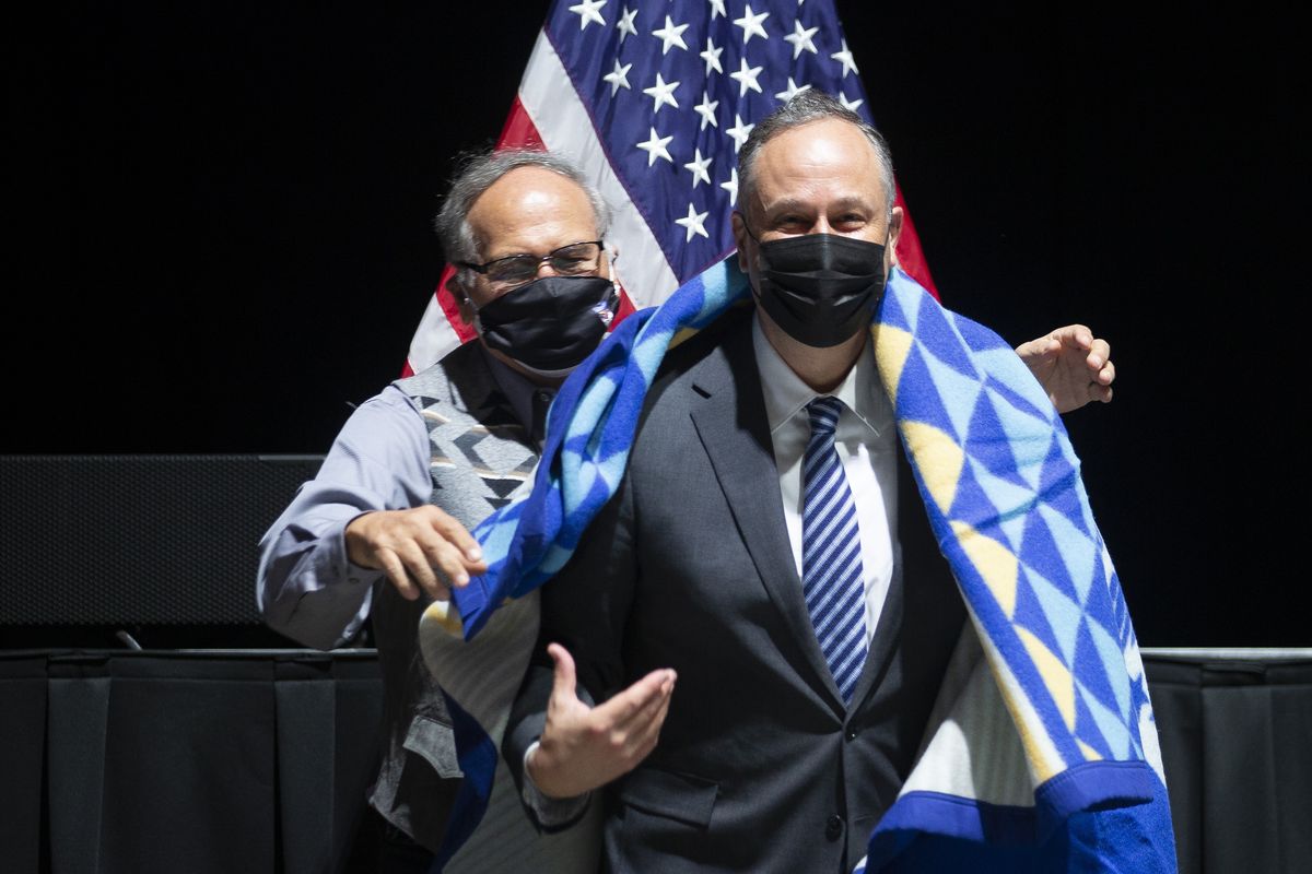 Yakama Tribal Chairman Delano Saluskin, left, drapes a gifted blanket over the shoulders of Second Gentleman Douglas Emhoff during a Yakama Nation Tribal Council meeting at Legends Casino, Tuesday, April 6, 2021, in Toppenish in Yakima County, Wash.   (Evan Abell/Yakima Herald-Republic via AP)