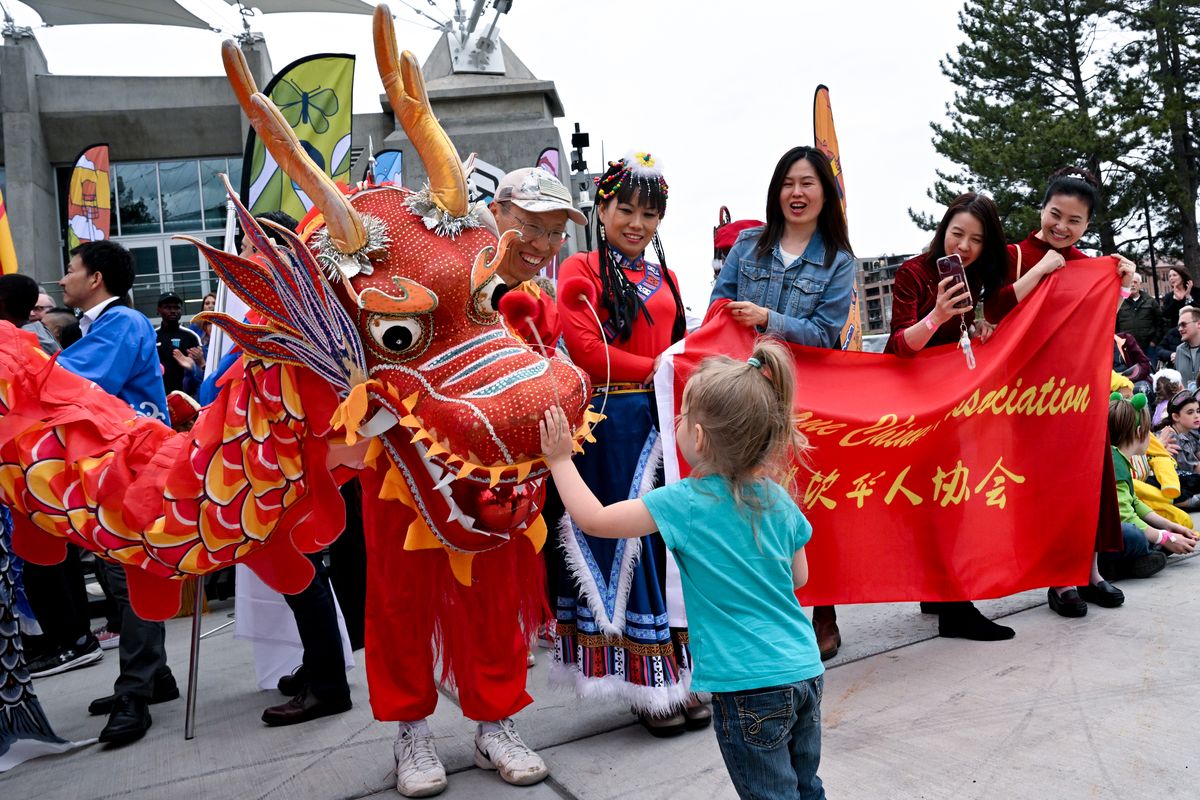 David Liu, left, with the Spokane Chinese Association smiles as youngster Hope Mitchell, 4, pets the nose of the Spokane Chinese Association’s dragon during the Expo ’74 50th Celebration Opening Ceremony - at the U.S. Pavilion on Saturday, May 4, 2024, in Spokane.  (Tyler Tjomsland/The Spokesman-Review)