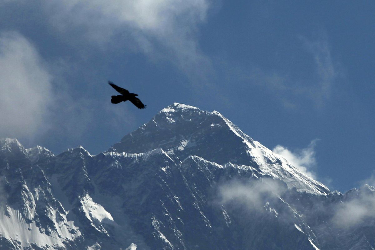 FILE - In this May 27, 2019, file photo, a bird flies with Mount Everest seen in the background from Namche Bajar, Solukhumbu district, Nepal. China and Nepal have jointly announced on Tuesday, Dec. 8, 2020, a new height for Mount Everest, ending a discrepancy between the two nations. The new official height is 8,848.86 meters (29,032 feet), slightly more than Nepal