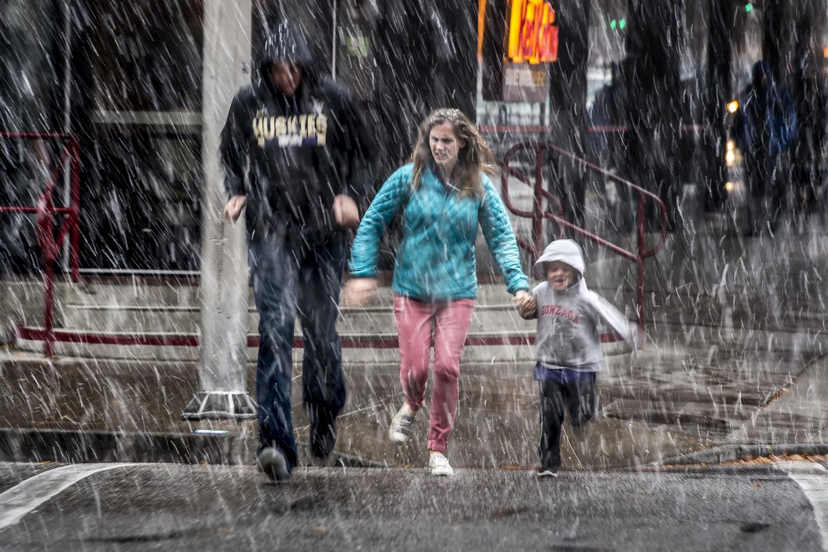 During a snow shower in downtown Spokane, Adam and Holly Jackson and their son Elliot, age 4, rush across  Main Avenue on their way to the Children’s Museum in River Park Square, Friday, Nov. 3, 2017. (Colin Mulvany / The Spokesman-Review)