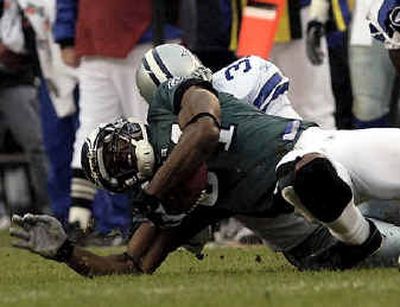 
Terrell Owens, bottom, sprains his left ankle and suffers a broken leg as he's tackled by Dallas' Roy Williams in the third quarter Sunday. 
 (Associated Press / The Spokesman-Review)