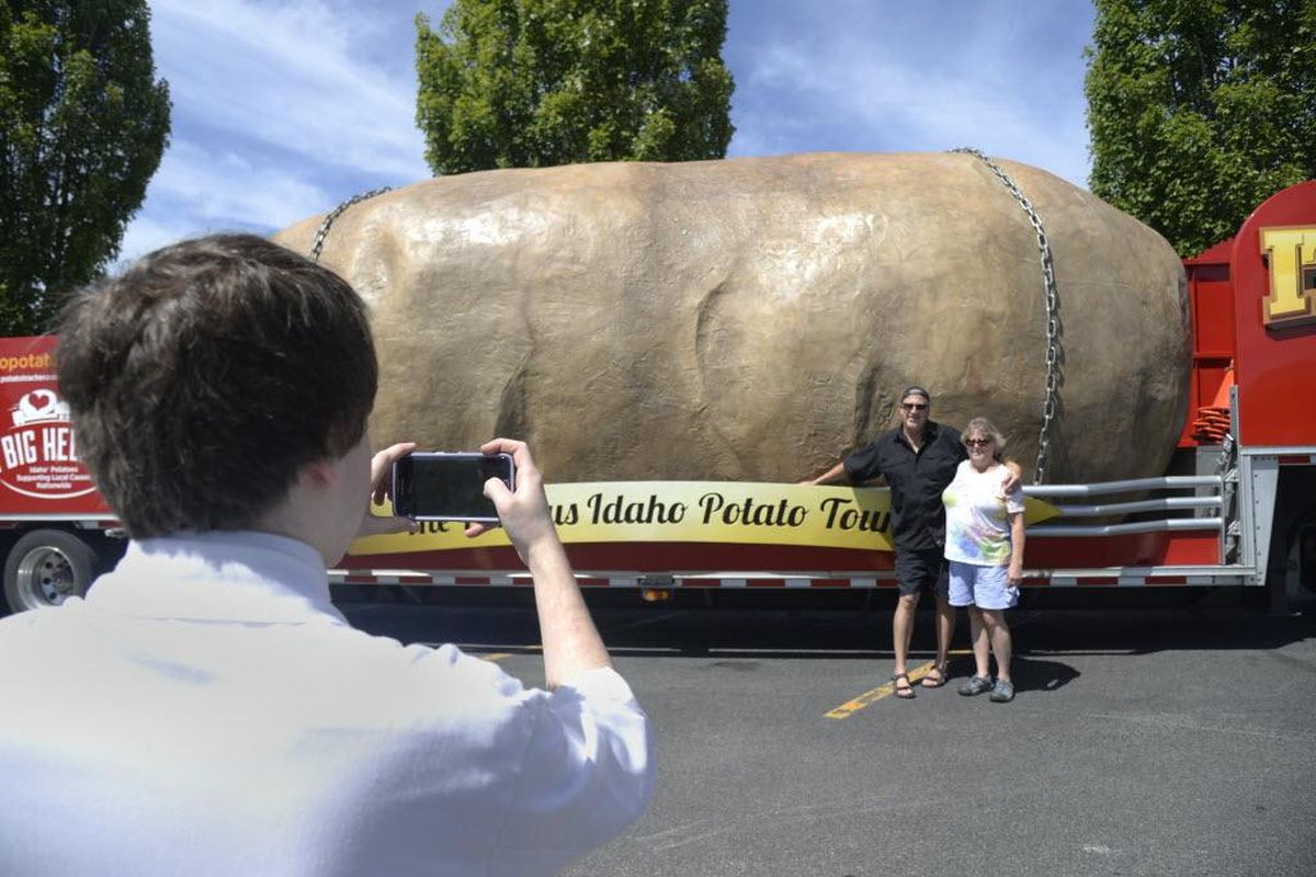 Ty and Patti Nelson have their photo taken by Max Rothenberg, left, outside of Super 1 Foods in Post Falls, Idaho, where the giant potato truck made a stop on June 22, 2016. Dozens stopped in to see the rolling attraction in the supermarket parking lot; the next day, it headed to Spokane. (Jesse Tinsley / The Spokesman-Review)