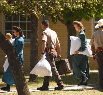 Fundamentalist Church of Jesus Christ of Latter Day Saints women and children from the YFZ Ranch are escorted from the First Baptist Church's Fellowship Hall to buses Sunday. Associated Press
(Associated Press / The Spokesman-Review)