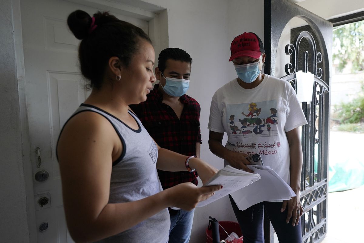 Sidewalk School founder Felicia Rangel-Samponaro, right, works with teacher Gabriela Fajardo, a 26-year-old Honduran seeking asylum in the United States, left, and assistant Victor Cavazos on Friday, Nov. 20, 2020, in Matamoros, Mexico. Like countless schools, the Sidewalk School went to virtual learning amid the coronavirus pandemic, but instead of being hampered by the change, it has blossomed.  (Eric Gay)