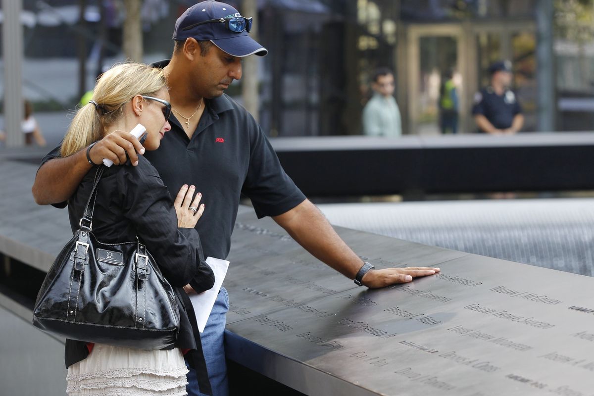Shauna Camp and Anthony Camp, who lost their uncle, Faustino Apostol Jr., in the 9/11 terrorist attacks, look at the panel inscribed with his name during the first day that the 9/11 memorial plaza was opened to the public at the World Trade Center site in New York. (Associated Press)